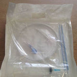 Sterile medical catheter kit with tubing and syringe sealed in clear packaging on table