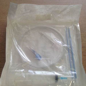 Sterile medical catheter kit with tubing and syringe sealed in clear packaging on table