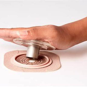 Hand pressing ostomy pouch baseplate for secure adhesive seal on skin