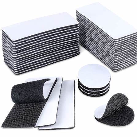 Stacked rectangular and round adhesive hook and loop fastener strips in black and white.
