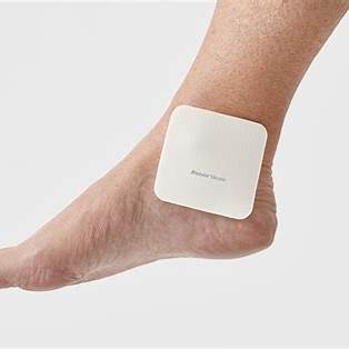 Adhesive medical patch on ankle for chronic condition care and pain relief