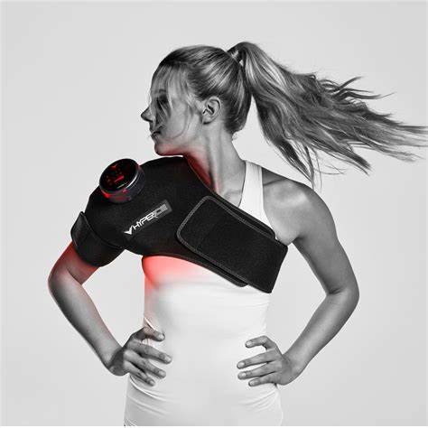 Woman wearing shoulder therapy wrap device with infrared light for pain relief