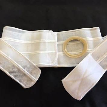 White ostomy support belt with circular opening for medical use on black background