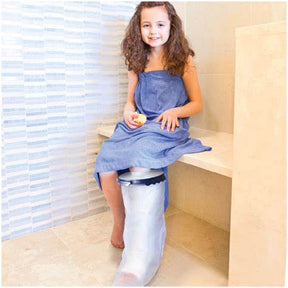 Smiling girl in bathrobe with waterproof leg cast cover sitting in bathroom